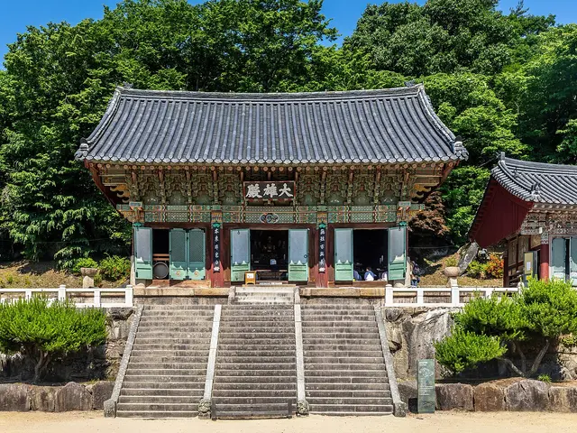 The main hall of Beomeosa, a Buddhist temple in Busan, South Korea, a wooden building with ornately painted eaves and a tiled roof reached by stone steps.