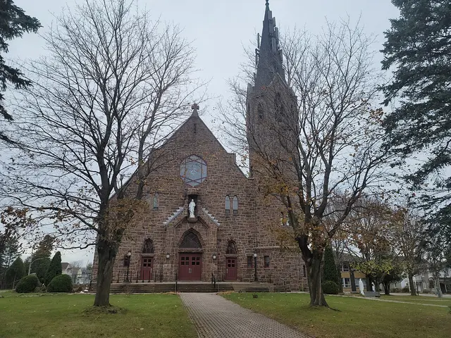 The stone Gothic-style front facade of the parish church of Sainte-Anastasie in Lachute, Quebec, with a statue above the entrance