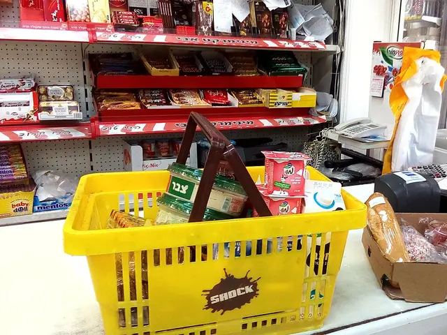 The interior counter of a small independent grocery store, with a shopping basket of goods on the counter and shelves stocked behind it