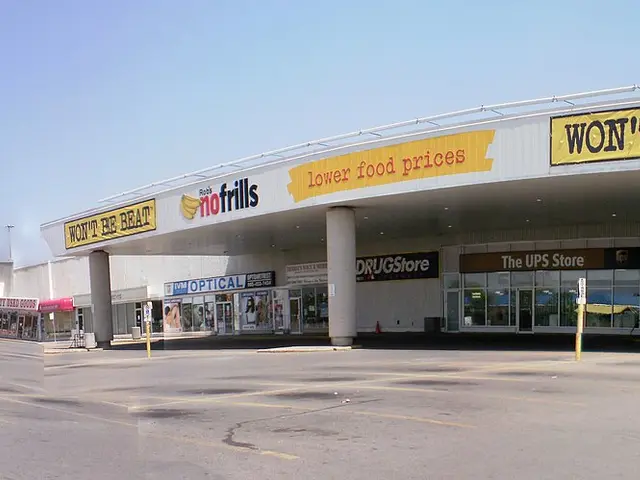 The exterior of a No Frills grocery store in a plaza, with its yellow "lower food prices" branding