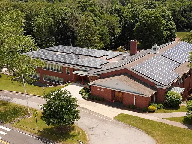 An aerial view of Saint Joseph Catholic Academy, a brick school building surrounded by trees and lawns.